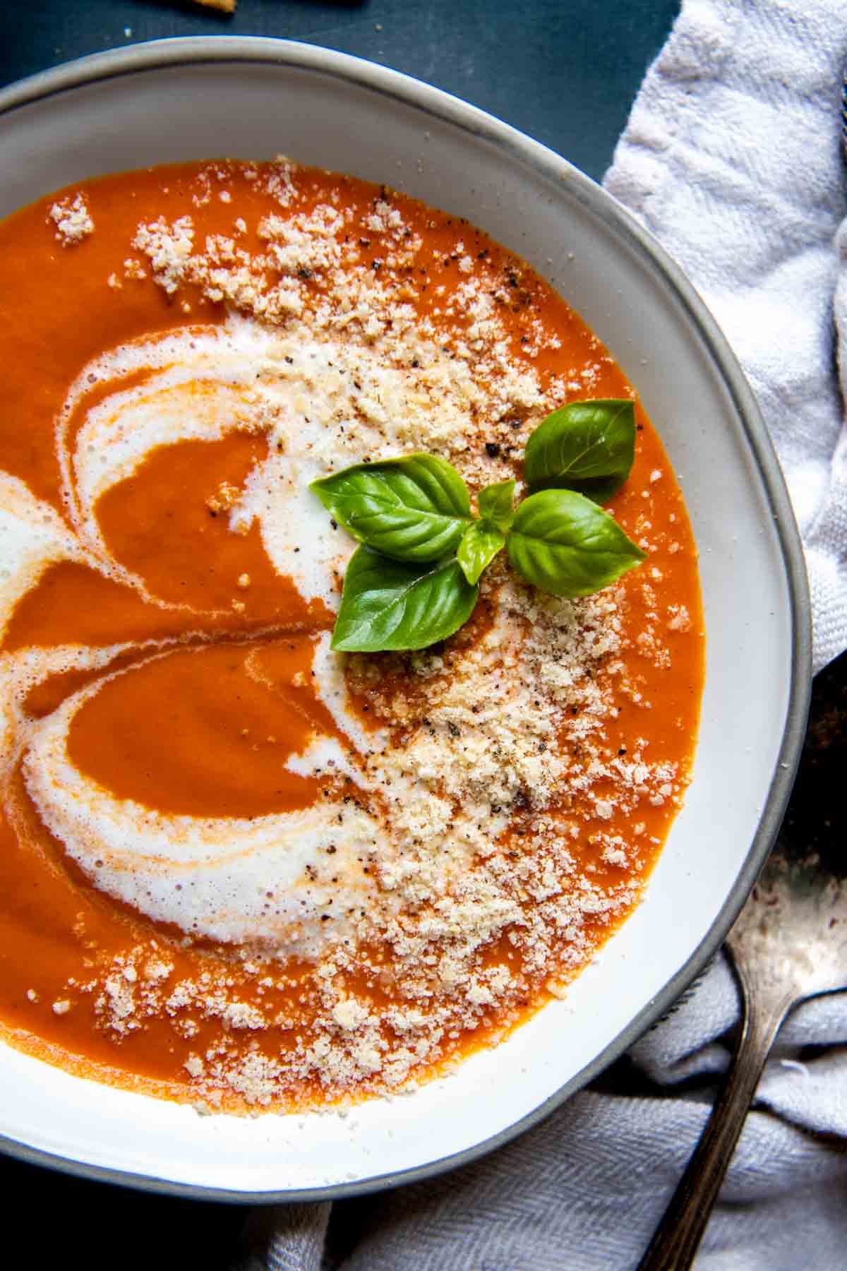 overhead shot of gluten-free tomato soup with parmesan and fresh basil on top.