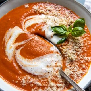 a spoon going into a bowl of tomato soup.
