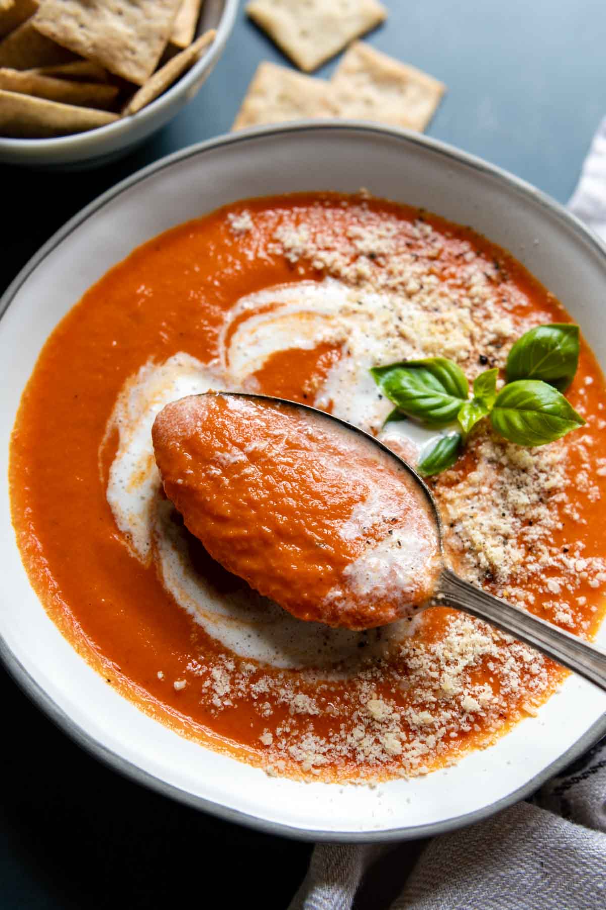 a spoon lifting out of a bowl of tomato soup.
