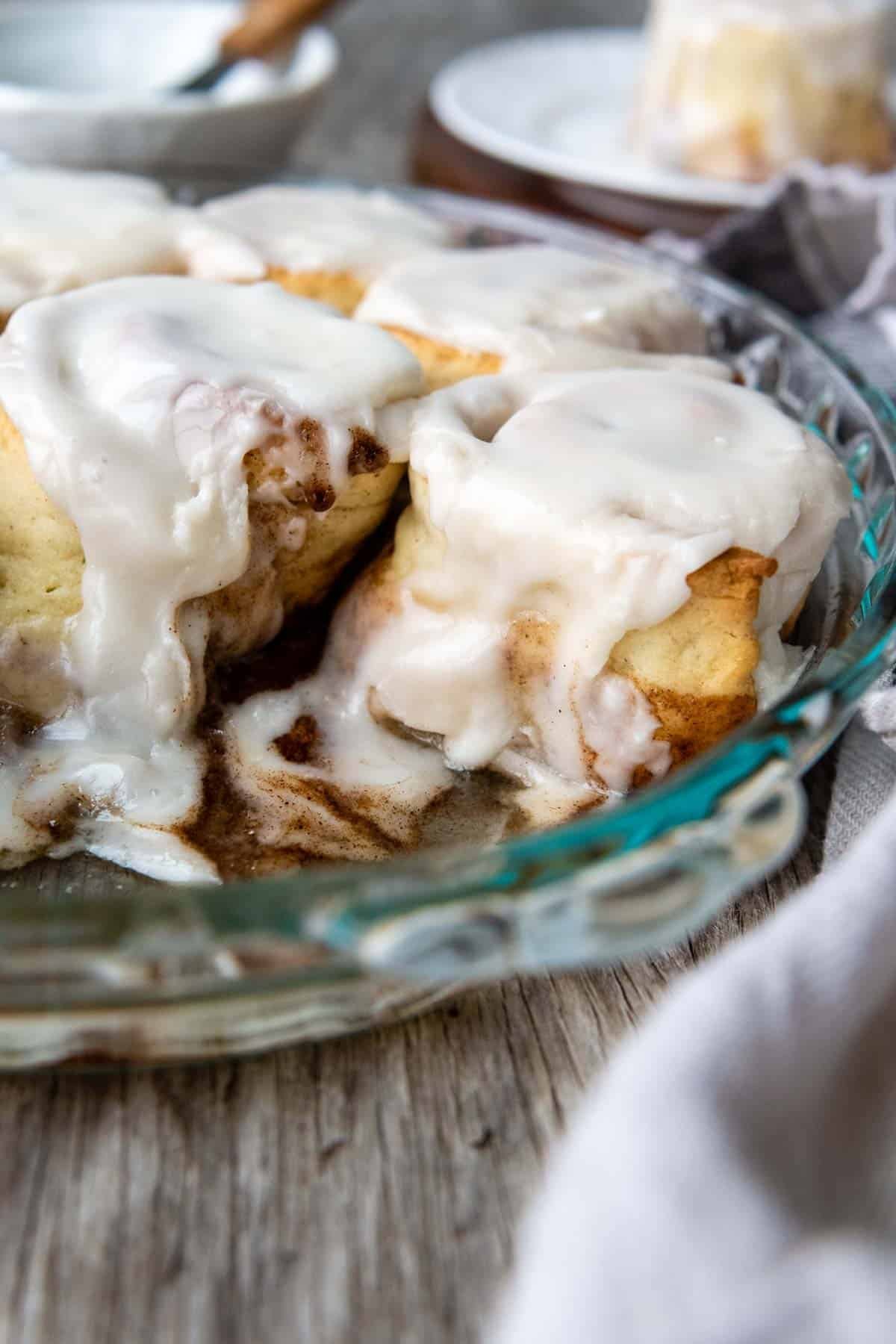 frosted cinnamon rolls in a glass pan.