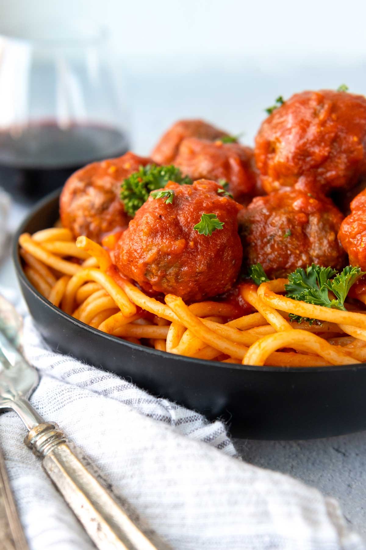 meatballs served over pasta in a black bowl.