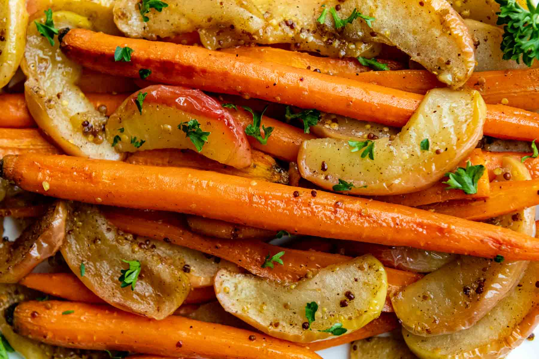 carrots and apples close up with parsley sprinkled on top.