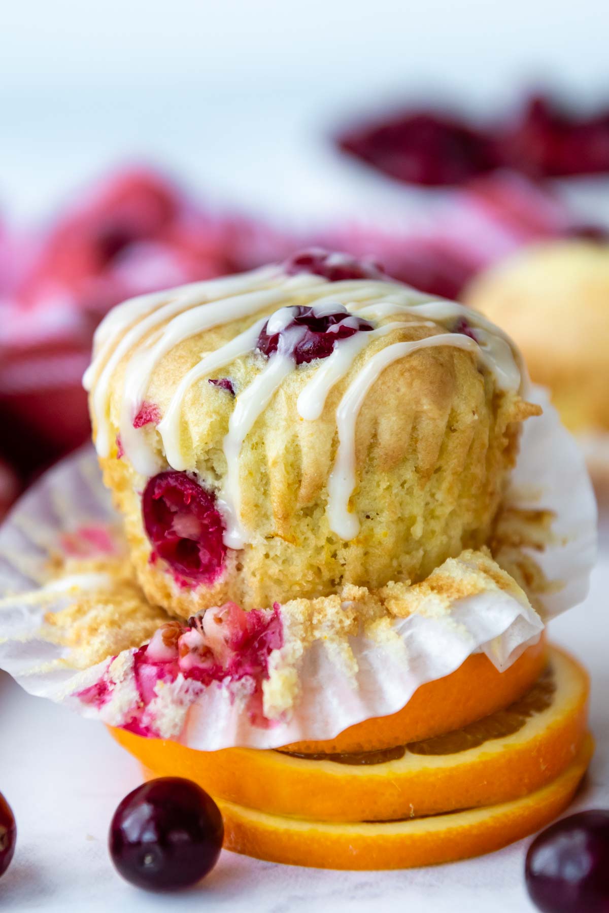 a cranberry muffin resting on sliced oranges with glaze on top.