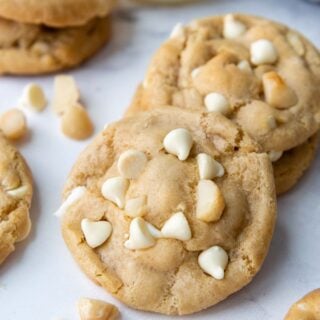 cookies laying a white marble surface with macadamia nuts and white chocolate chips.