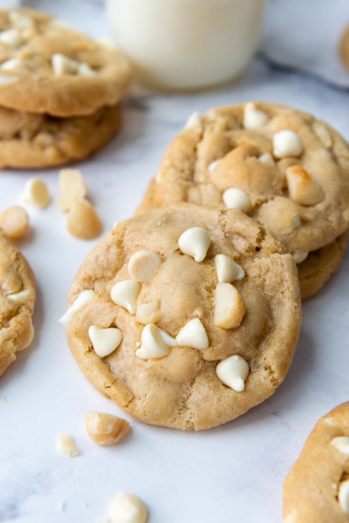 cookies laying a white marble surface with macadamia nuts and white chocolate chips.