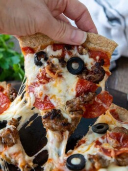 a slice of pizza being pulled with cheese dripping down.