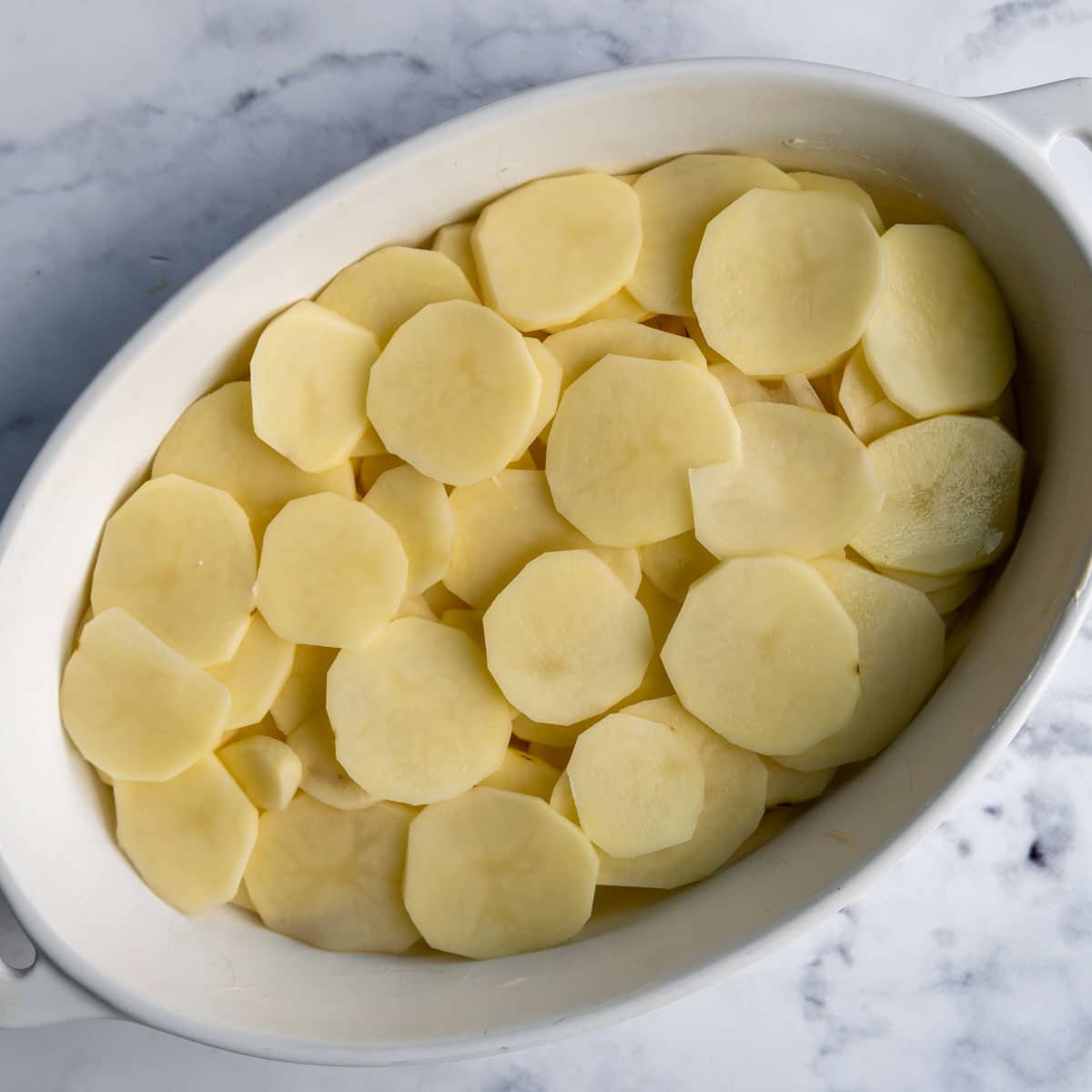 a layer of sliced unbaked potatoes in a baking dish.
