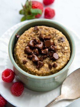 overhead shot of mug cake in a green dish with berries around.