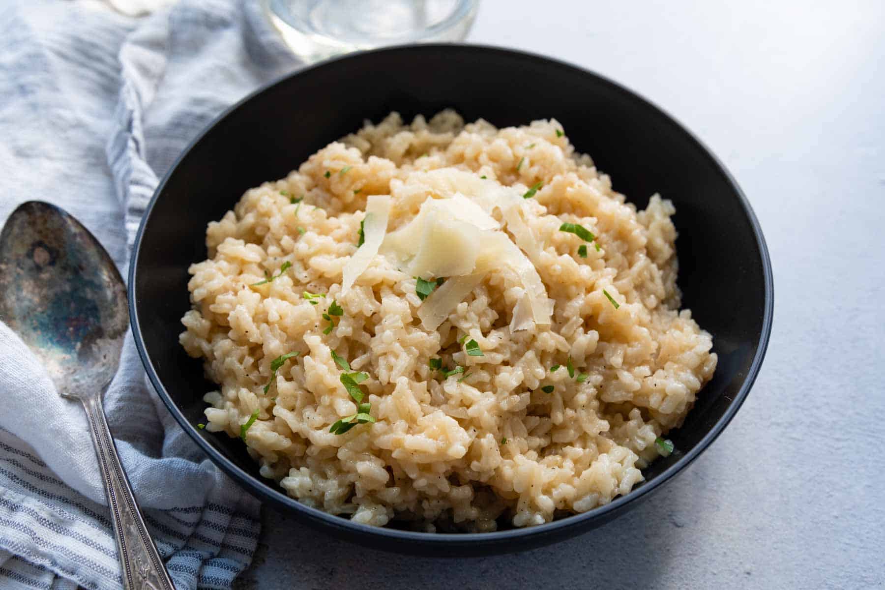 risotto in a black bowl with fresh parmesan on top.