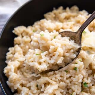 a spoon holding up a bite of risotto.