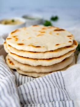 a stack of flatbreads on a white towel.