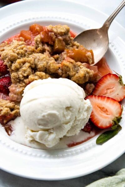 rhubarb crisp on a white plate with ice cream.