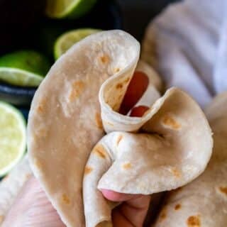 a flour tortilla scrunched up in a hand.