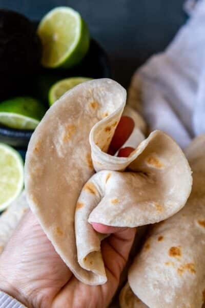 a flour tortilla scrunched up in a hand.