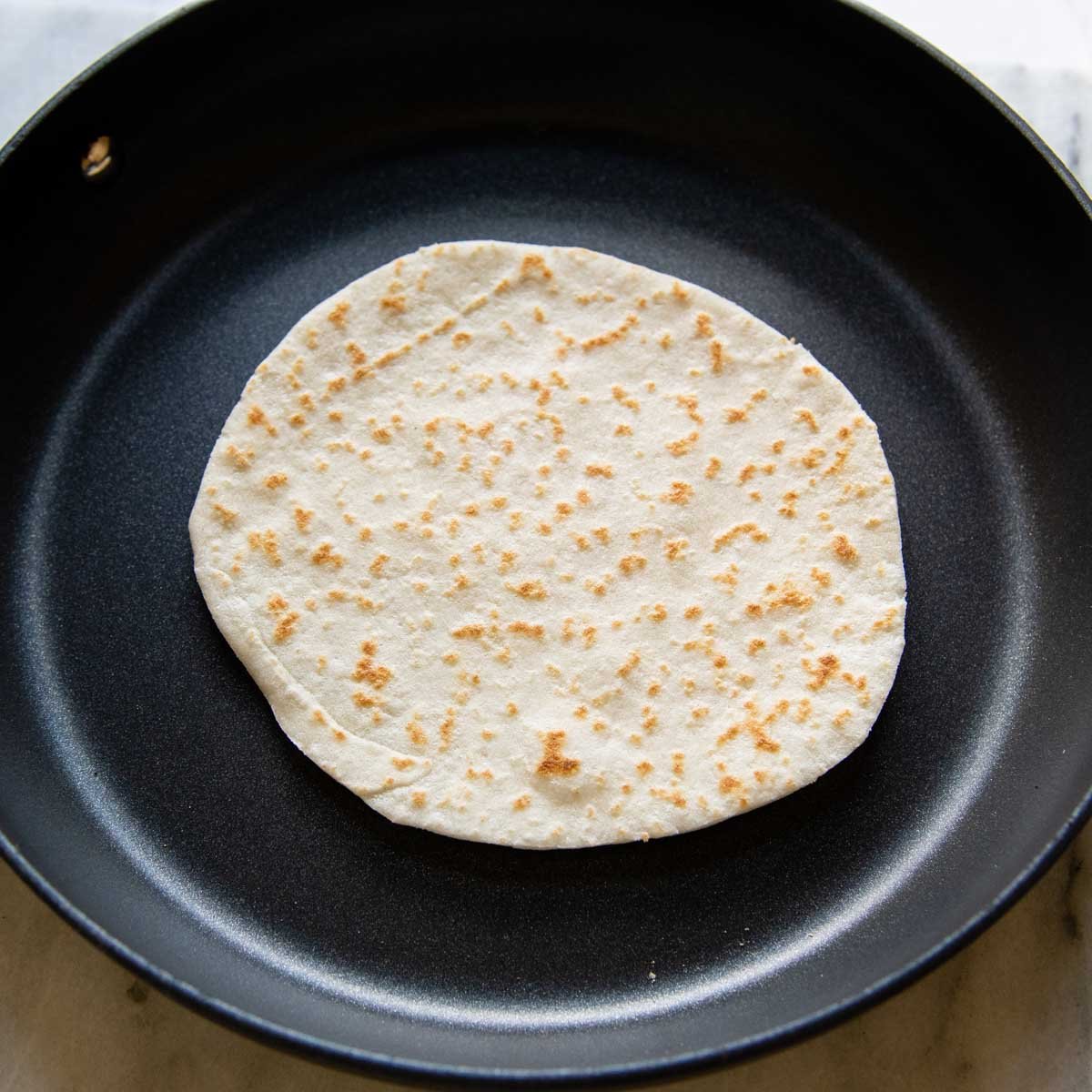 a gluten free tortilla being cooked in a skillet.