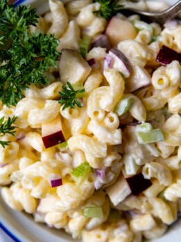 a close up of macaroni salad in a white bowl.