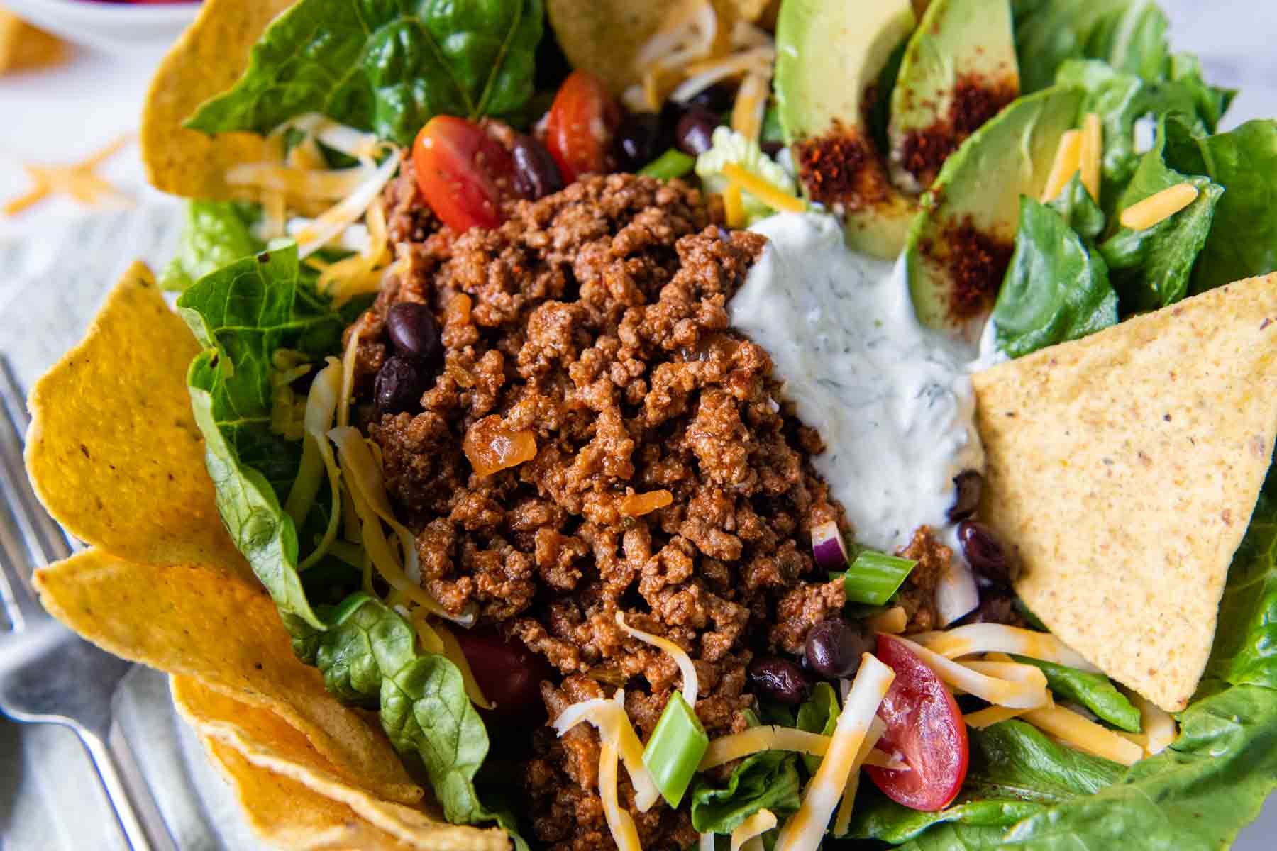 close up of taco meat on top of a salad.