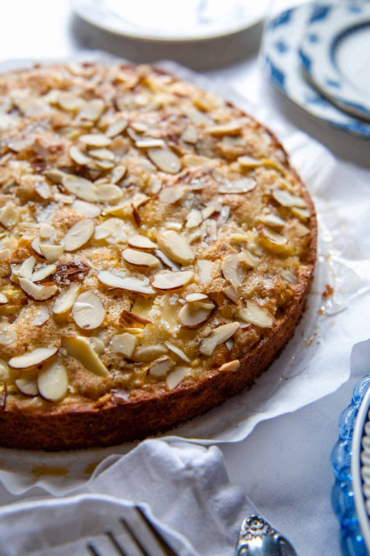 an almond apple cake with serving plates surrounding it.