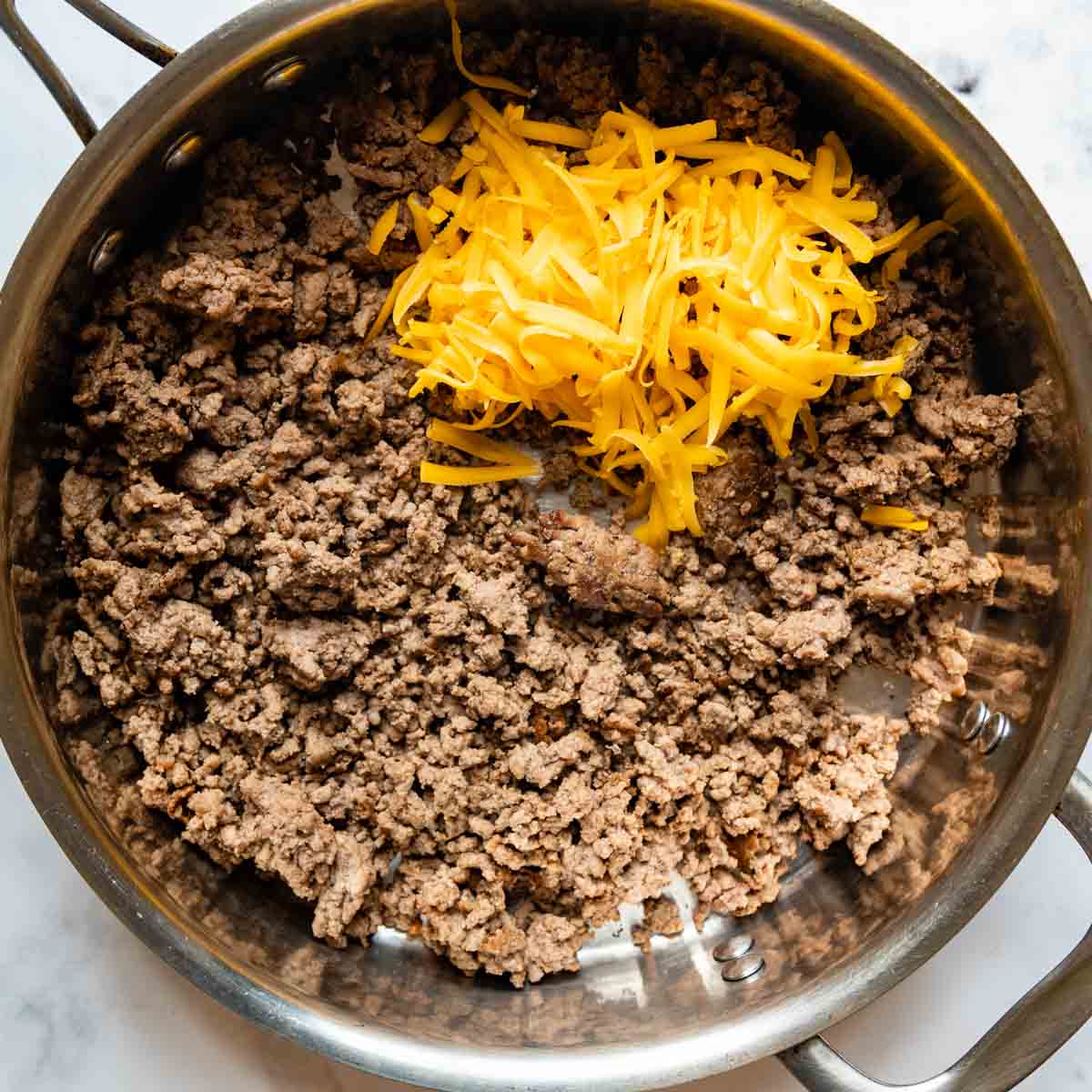 ground beef in a skillet with cheese.