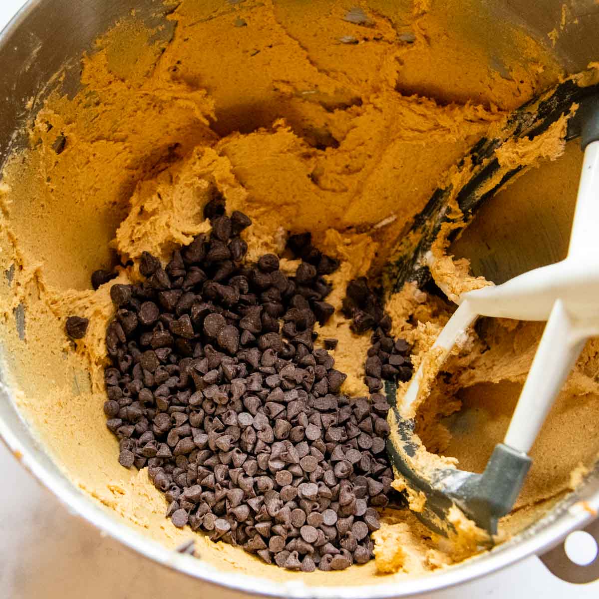 chocolate chips being added to the cookie dough.