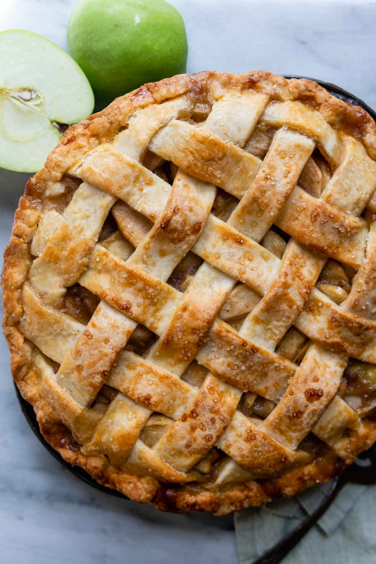 overhead of the apple pie with sliced apples next to it.