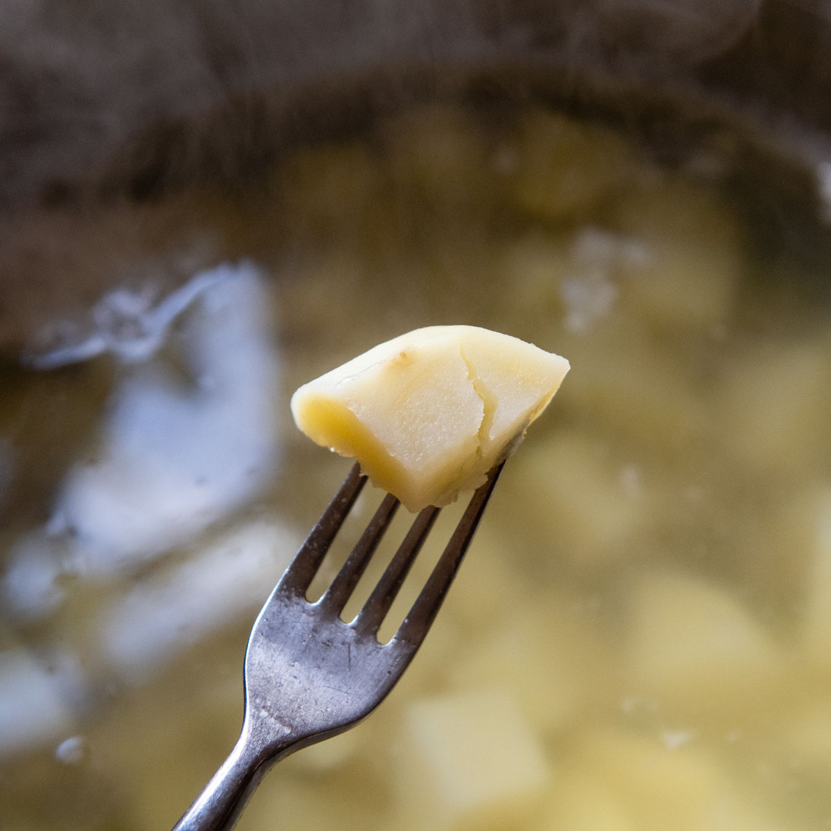 a fork piercing a boiled potato.