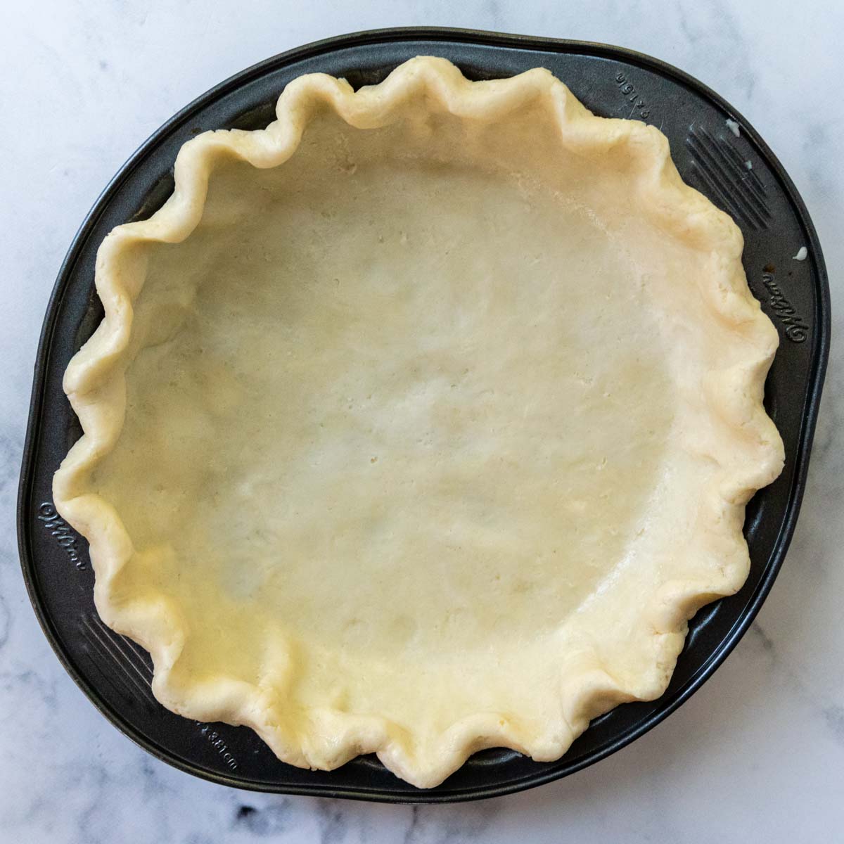 an unbaked pie crust in a metal pan.