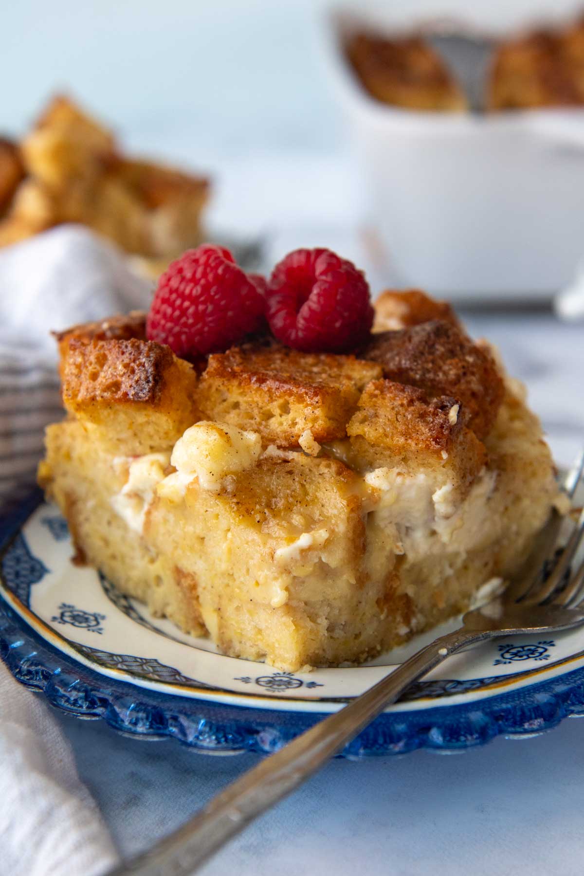 a slice of french toast bake on a blue plate with fresh berries on top.