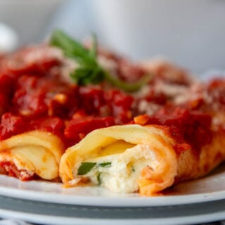 close up of the inside of manicotti on a white plate.