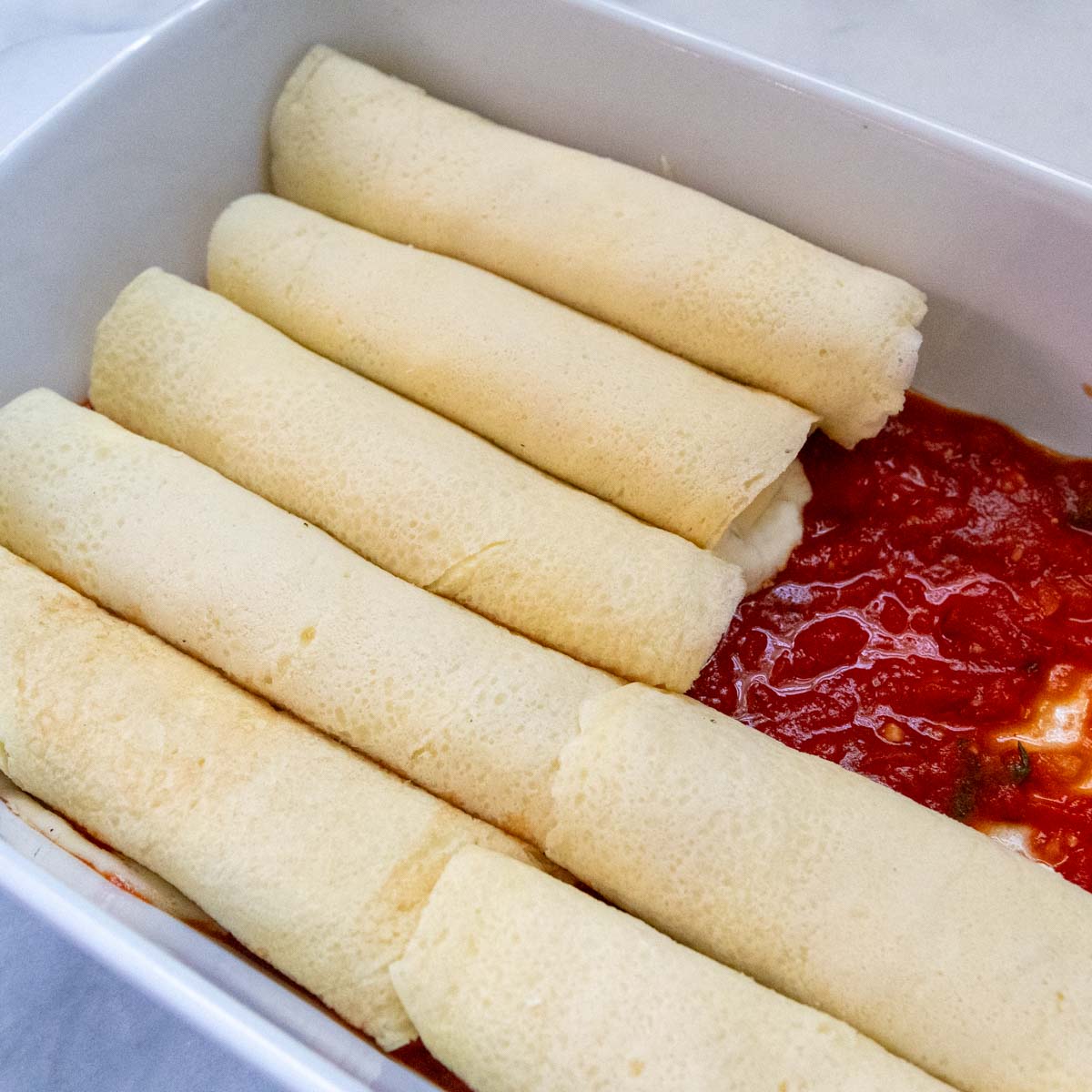 unbaked manicotti lined up in a casserole dish.