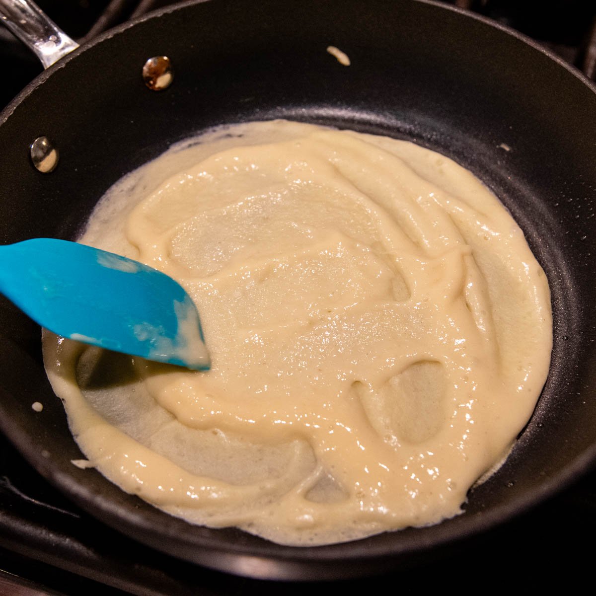 the batter being spread in a small skillet.