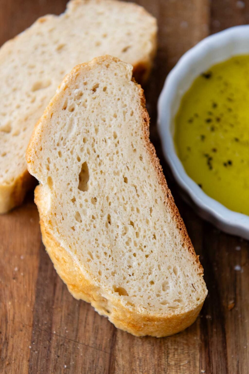 a slice of Italian bread resting next to a small bowl of olive oil.