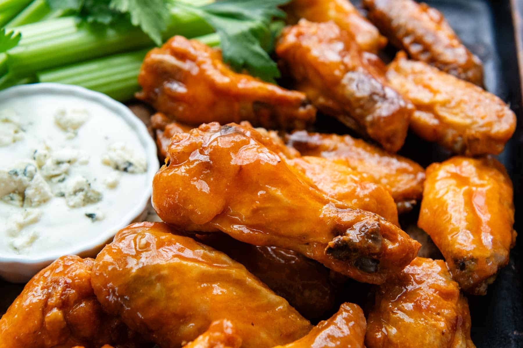 buffalo wings with a small bowl of dressing and celery in the background.