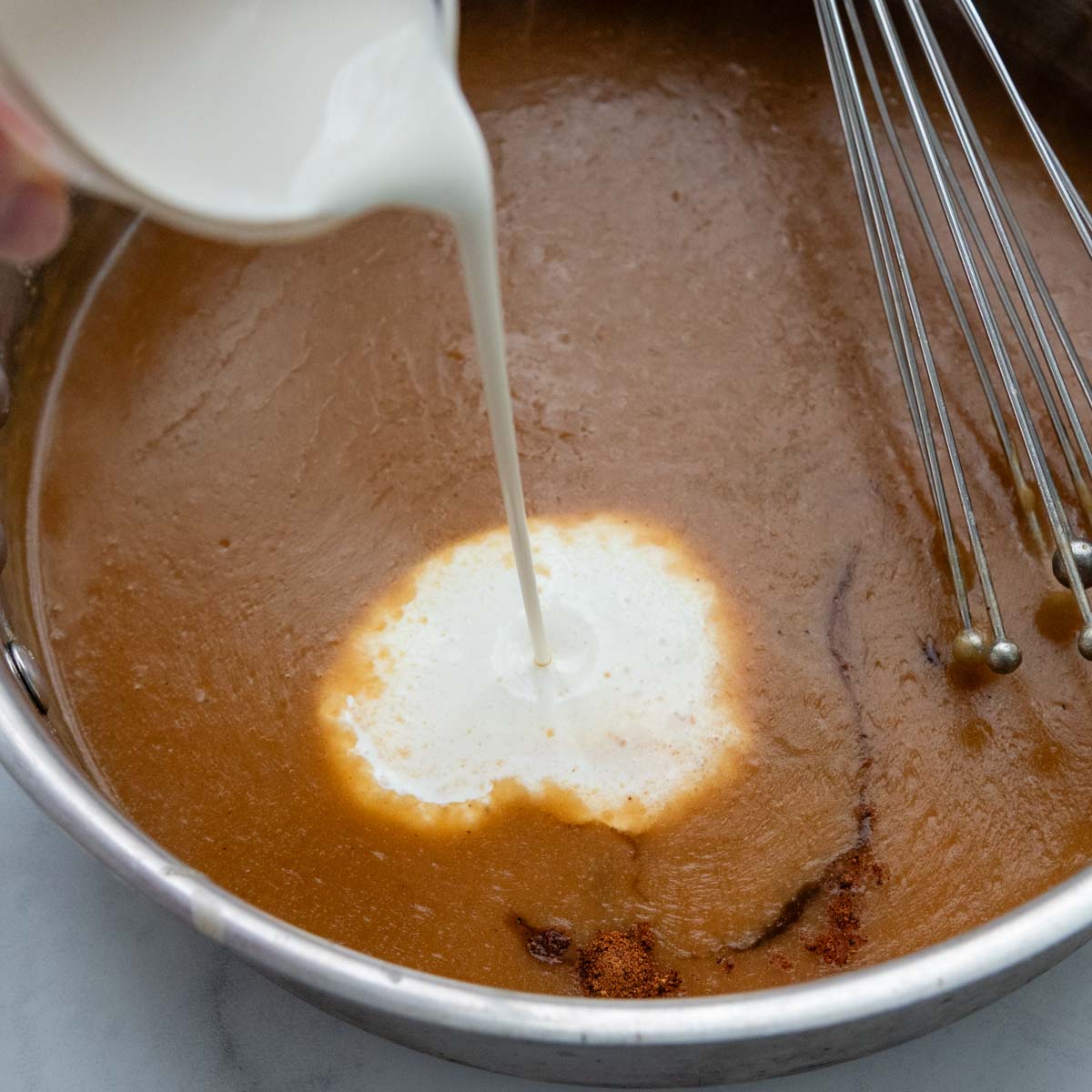 cream being poured into the gravy.