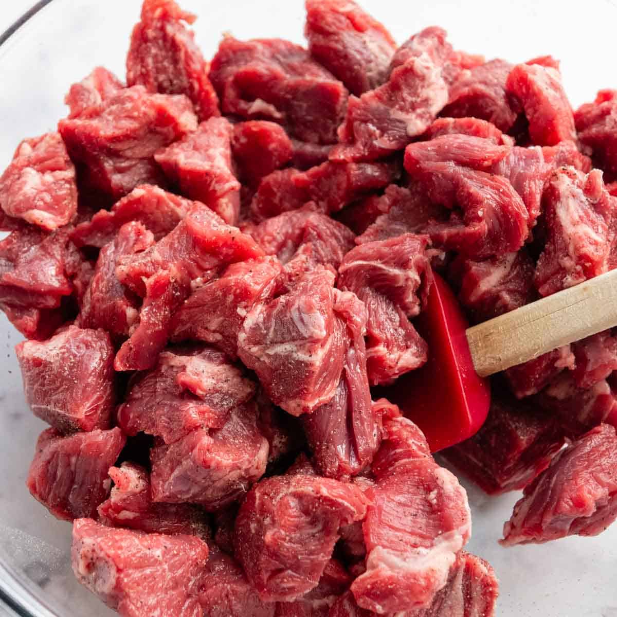 meat being stirred with salt and pepper in a bowl.