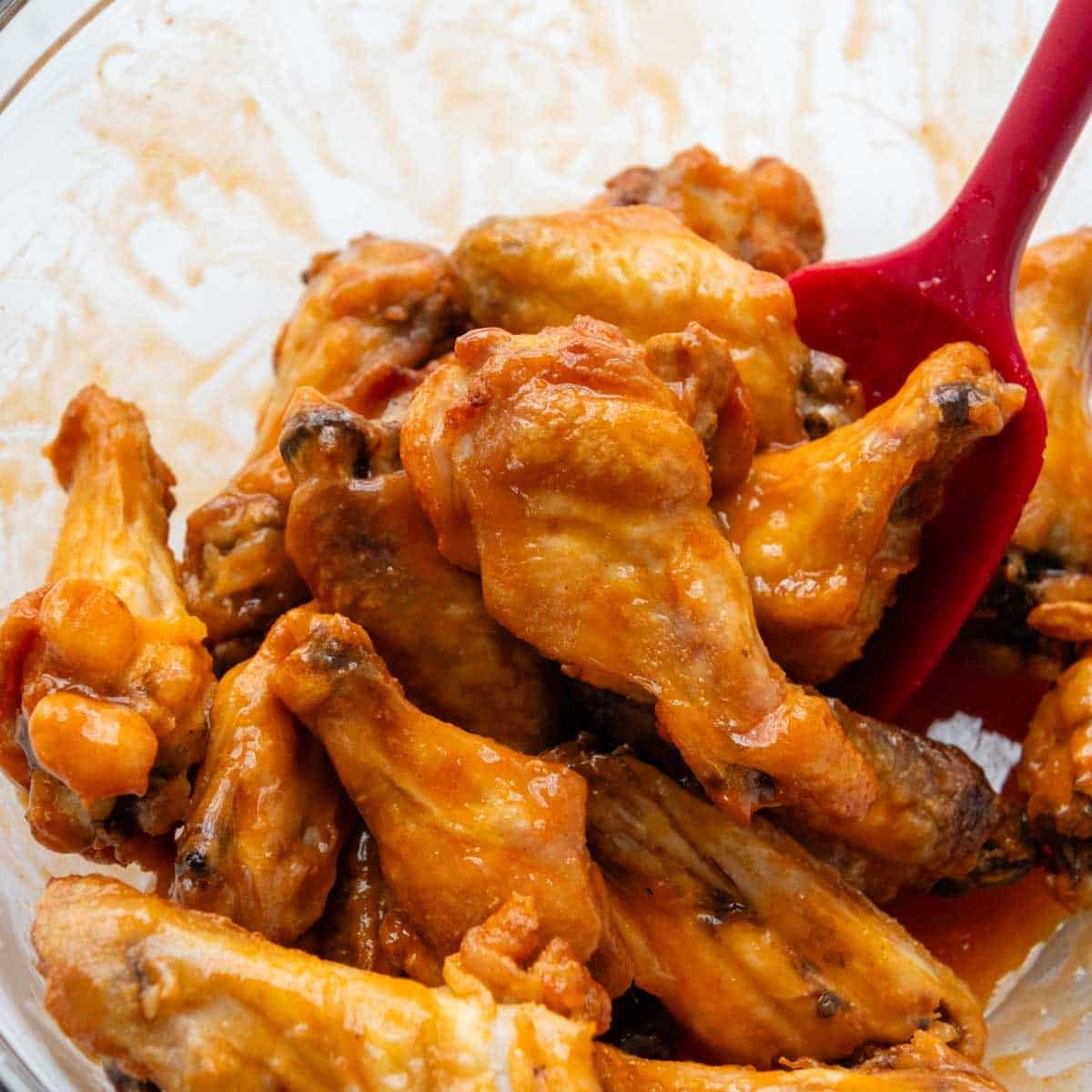 baked wings in a bowl with buffalo sauce.