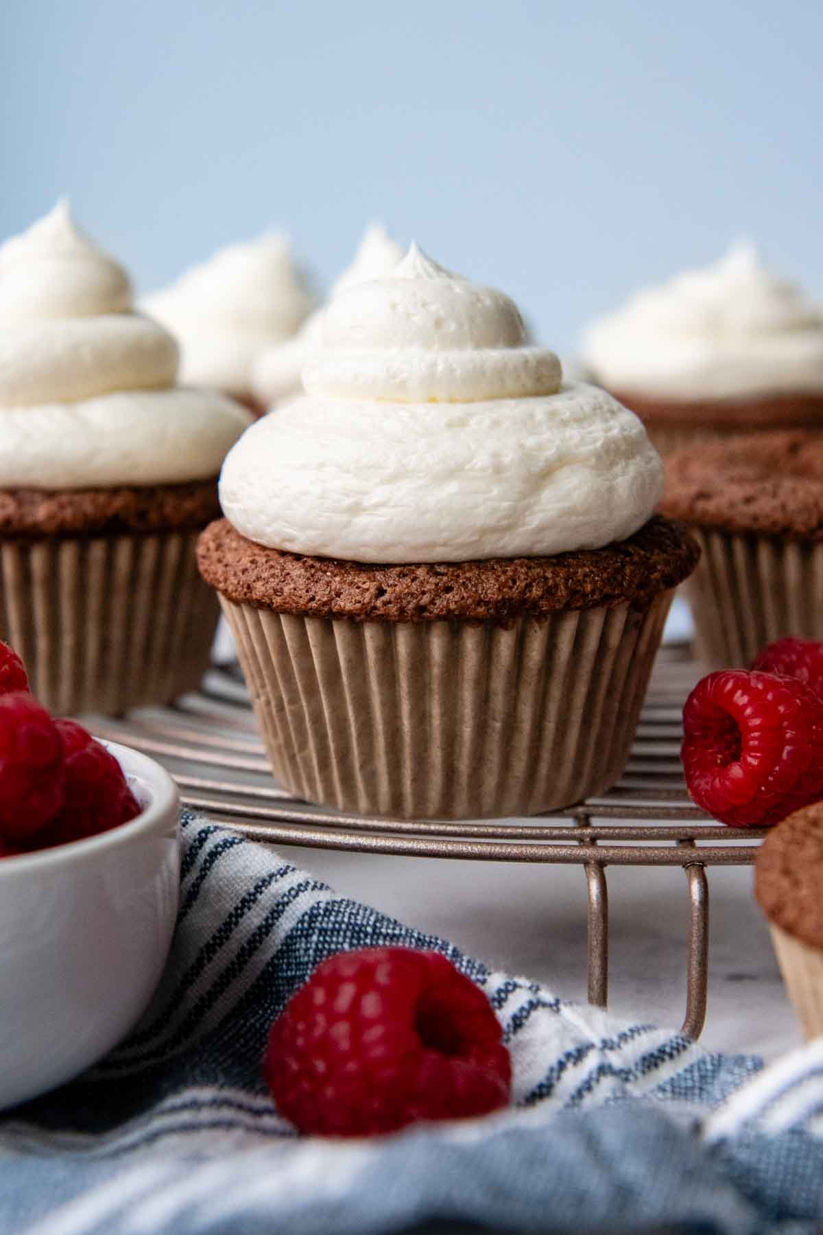 chocolate cupcake on a cooling rack and raspberries scattered around.
