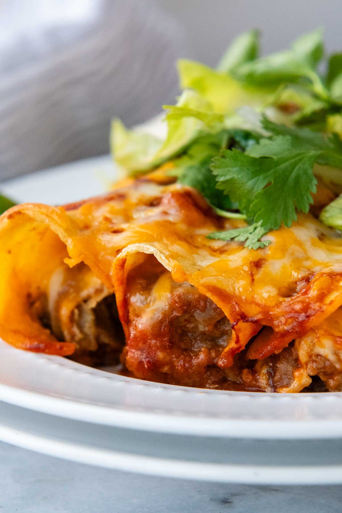 3 enchiladas on a plate with a close up of the filling.