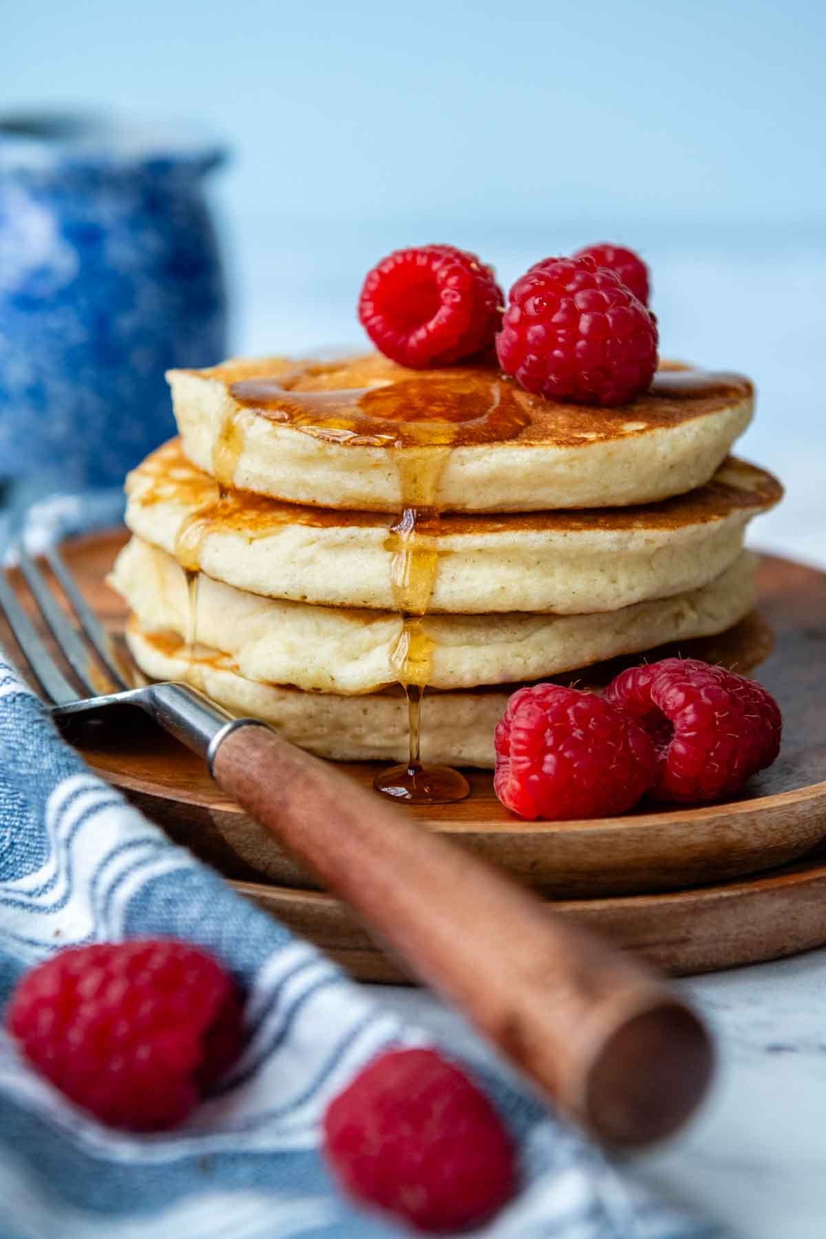 a stack of pancakes with raspberries and syrup on top.