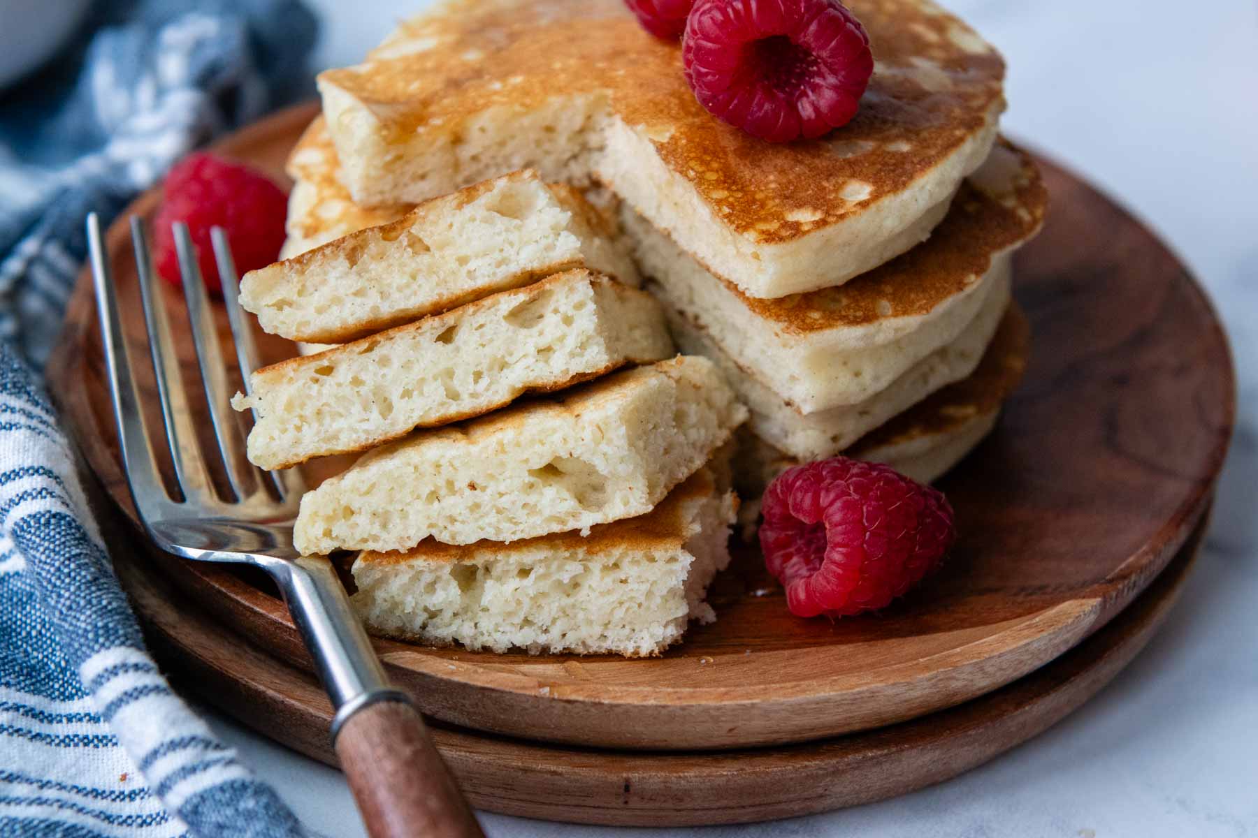 a bite of pancakes cut out on a wooden plate.