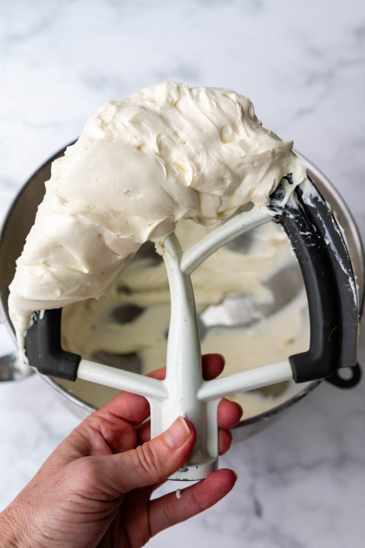 a beater holding up cream cheese frosting.
