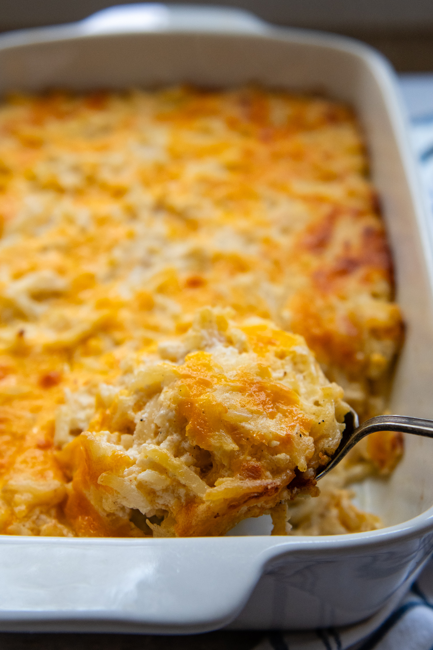 Casserole in a white baking dish with a serving being lifted out by a spoon.