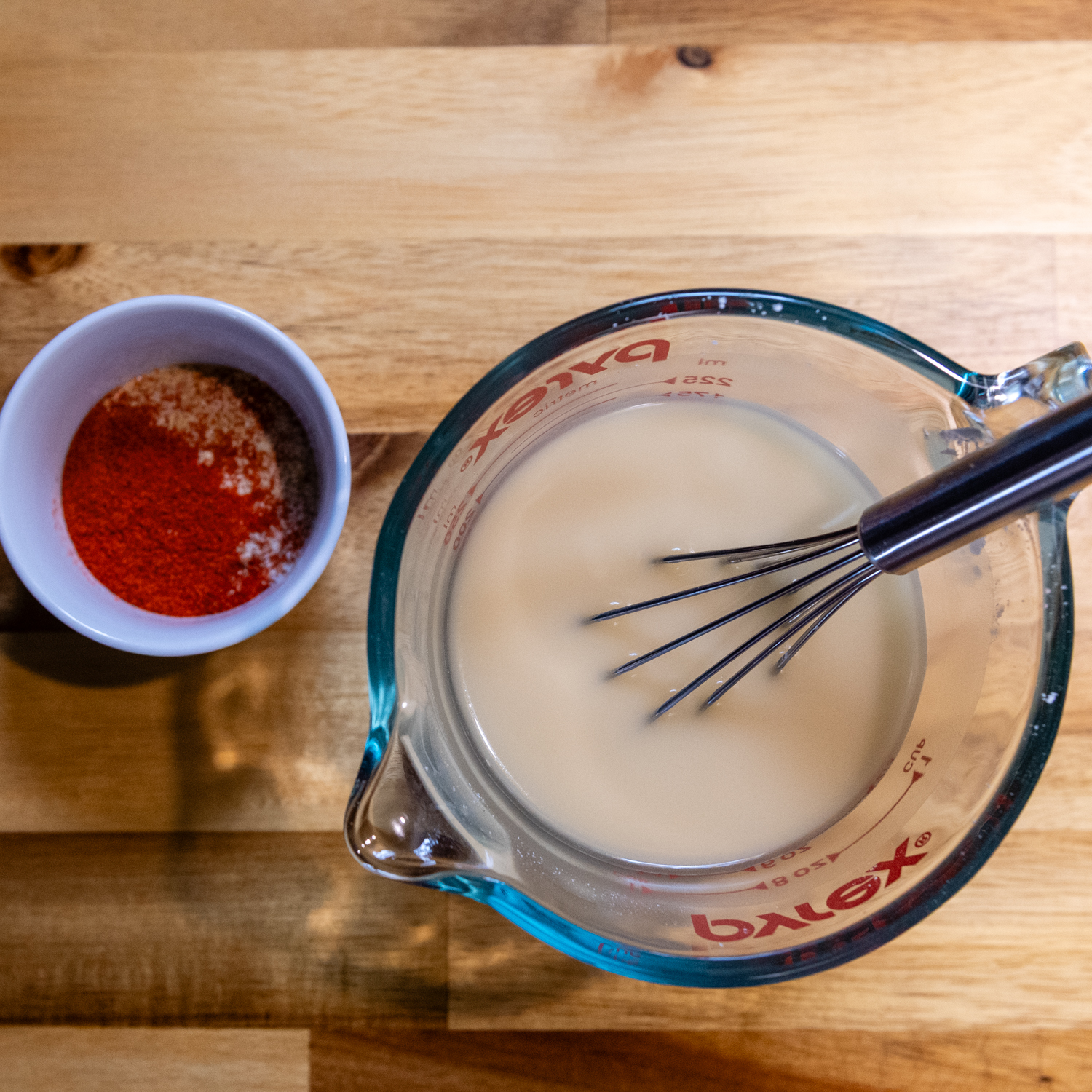 Liquid ingredients being whisked in a glass measuring cup.