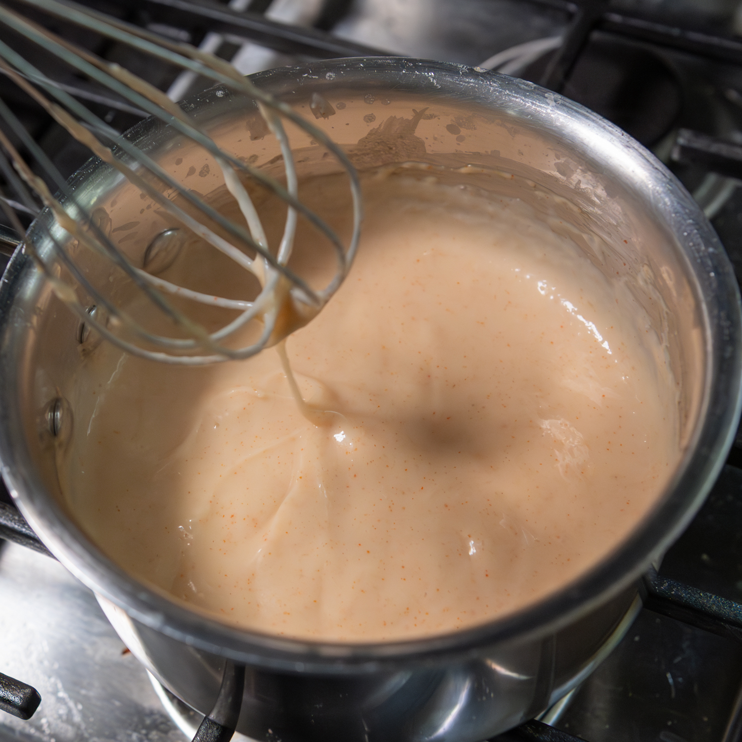 Creamy sauce being whisked in a pot.