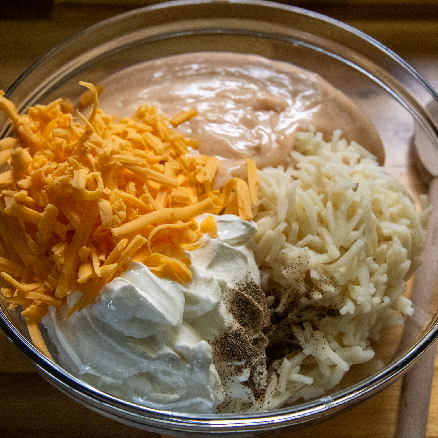 Shredded cheese, sour cream and hash browns being added to cream sauce.