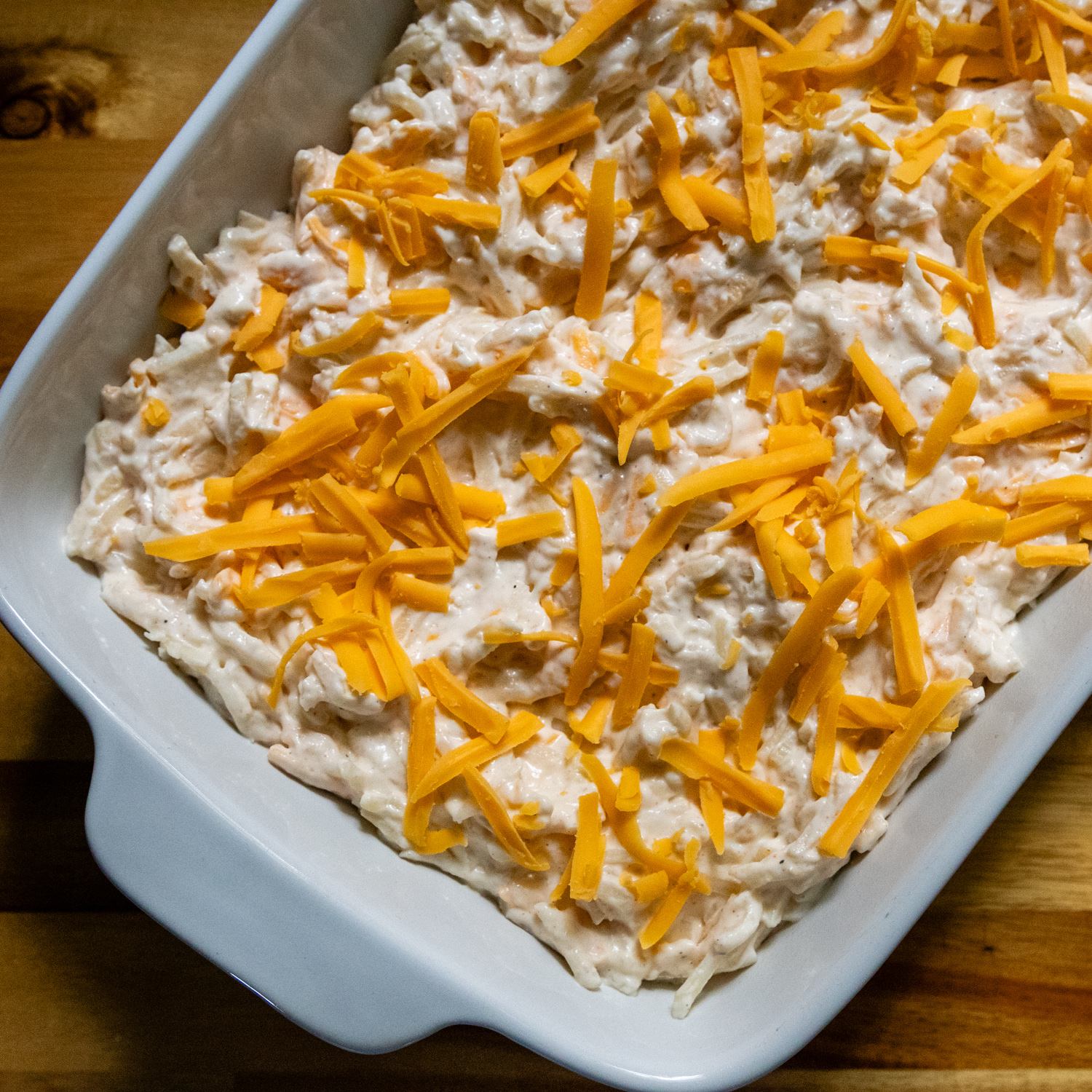 Uncooked combined casserole ingredients in a white baking dish.