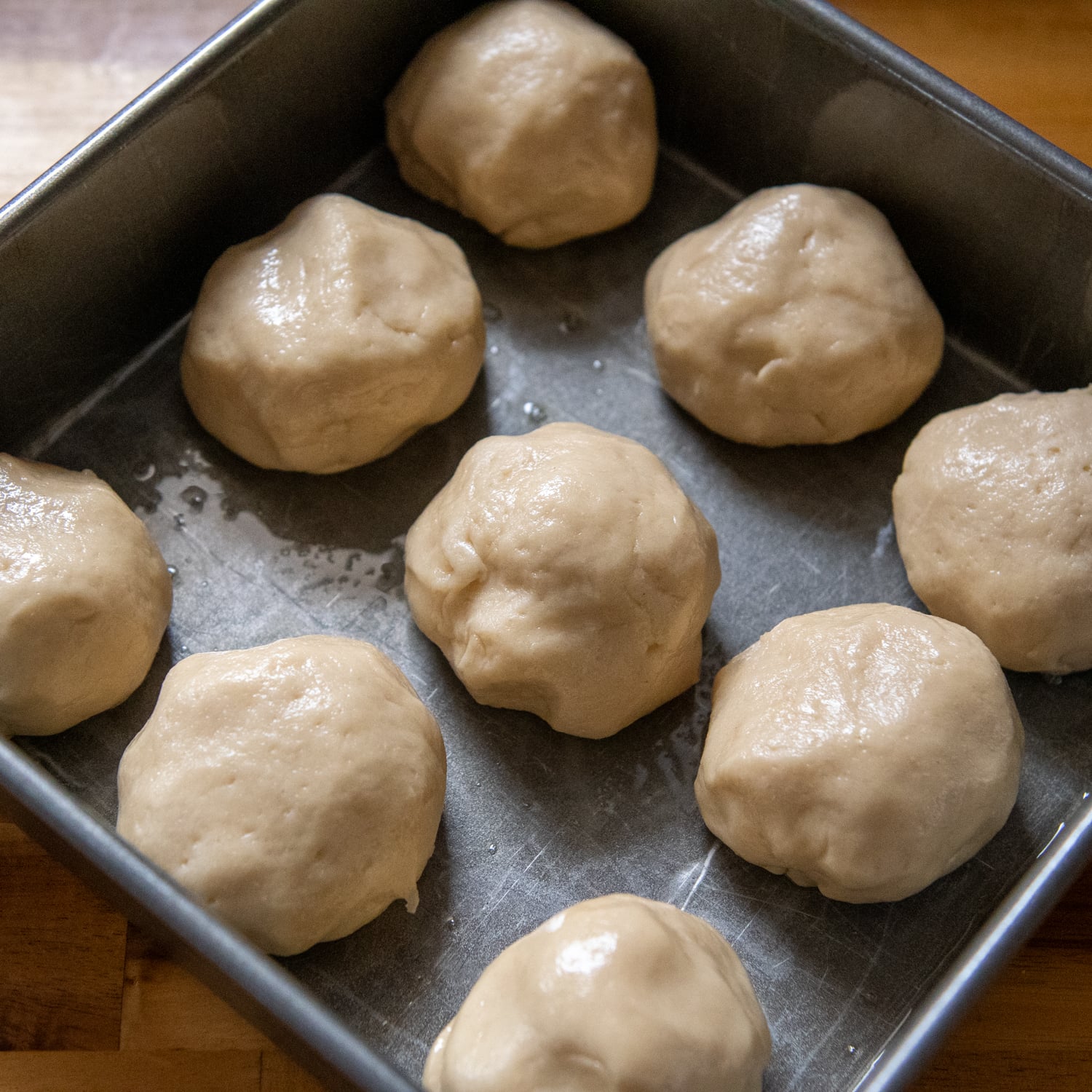 Dough balls placed in a baking pan.