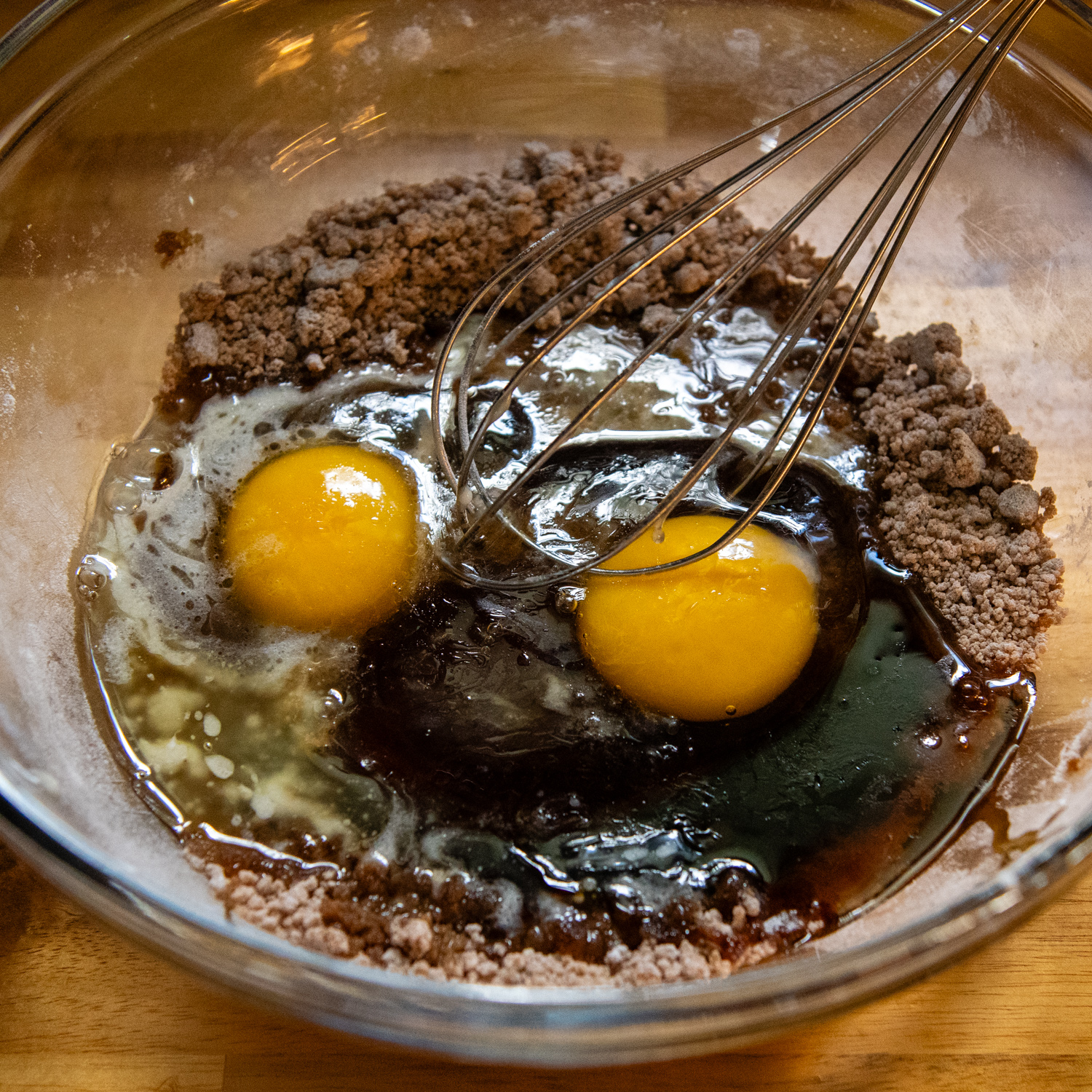 Topping ingredients that include eggs being whisked in a glass bowl.