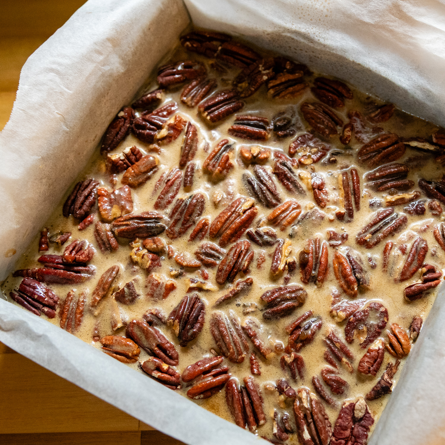 Pecan topping on top of crust in prepared baking pan.