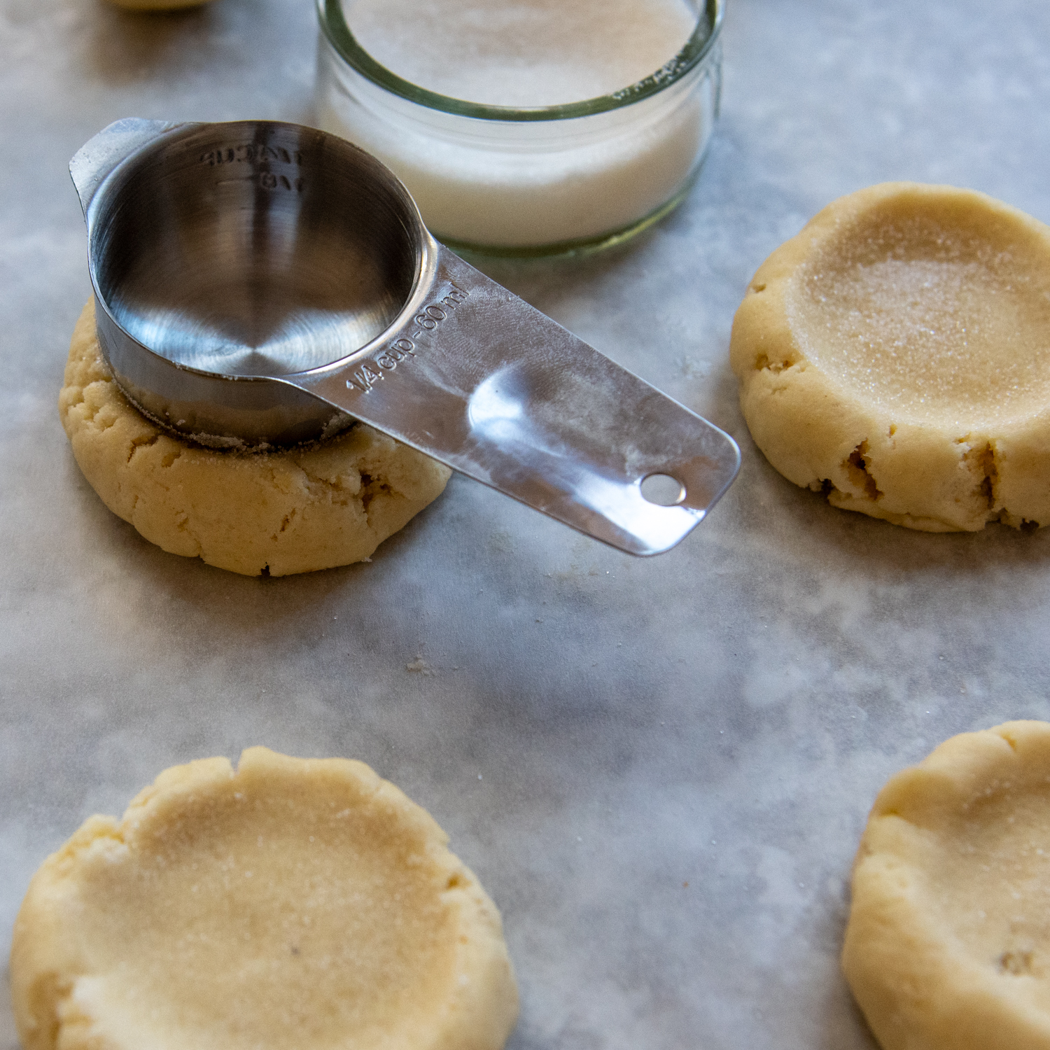 Measuring cup being used to create a well in the center a cookie.